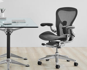 Herman Miller Aeron office chair near a glass office desk on light wooden floor