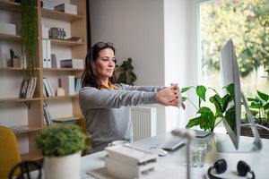 woman working at a used office desk with computer, office accessories and plants