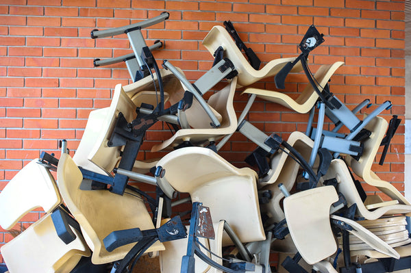 Go to article: Pile of broken used office chairs on brick wall background.