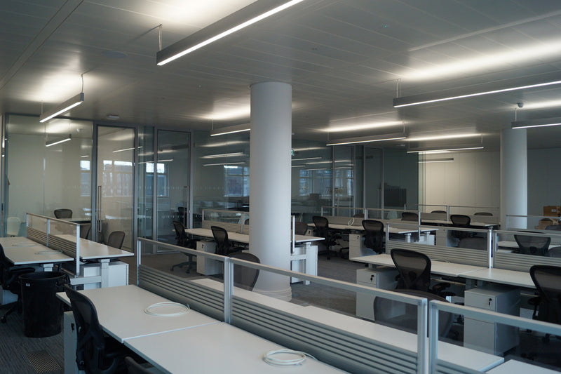 A London office interior with 25 workstations compirisng of white height-adjustable desks with desk dividers, white lockable office pedestals and black mesh herman miller aeron chairs. used office furniture