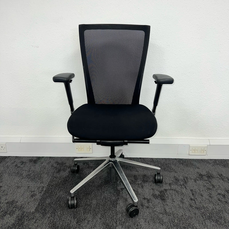 frontal view of a esh backrest used office chair on grey carpet