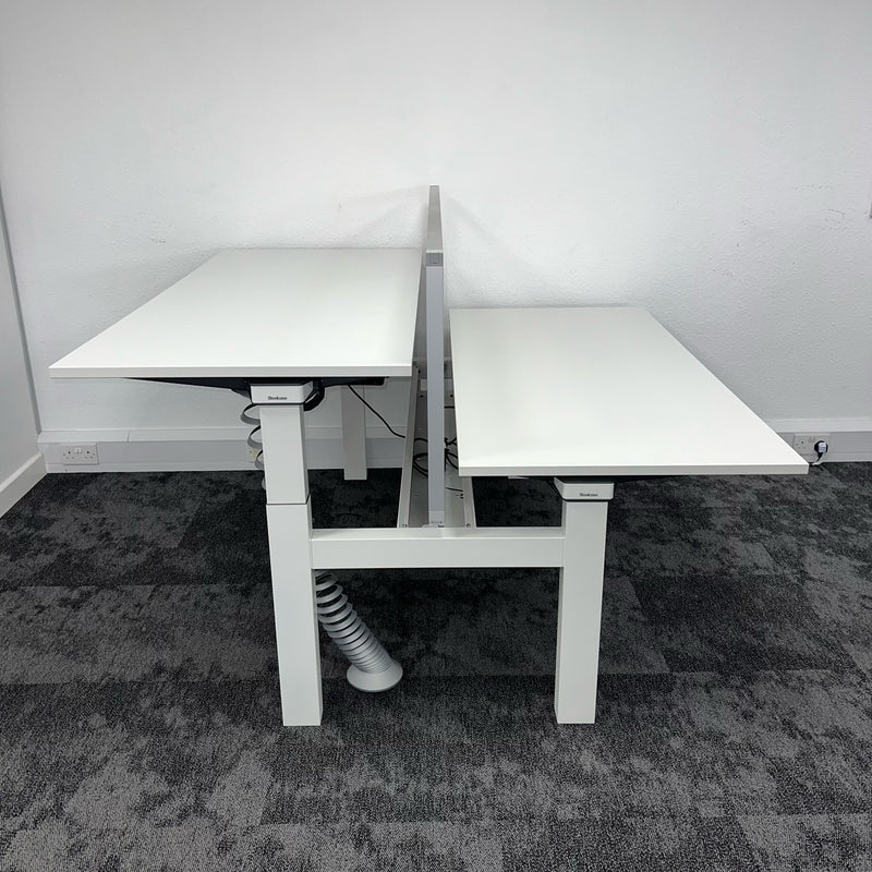 side view of a pod of two used bench desks. second hand office furniture, white height-adjustable bench desk by Steelacase